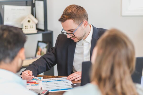 A real estate agent explaining and showing something on a piece of paper to his clients