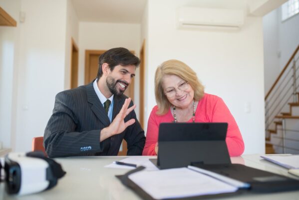 text: A gentleman and a lady looking at a tablet while smiling