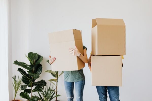 two people carrying cardboard boxes