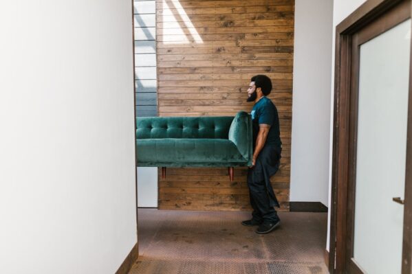 Professional movers carrying a green sofa