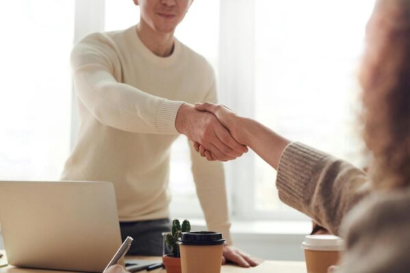 People shaking hands over a desk.