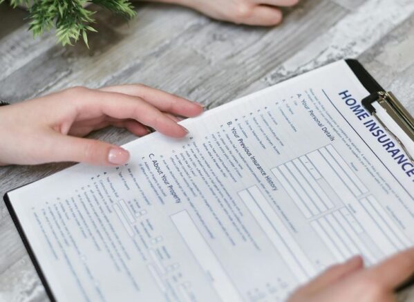 A person reviewing a home insurance application form on a clipboard