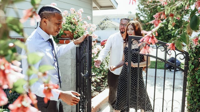 couple in front of the gate and a man opening the gate